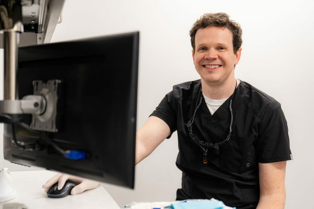 Dr. Hickey facing computer monitor and smiling at camera